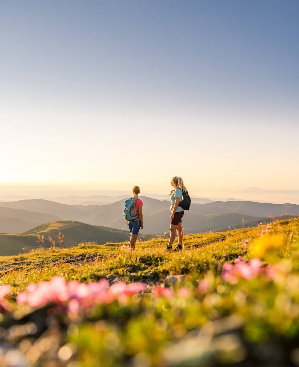 zwei Personen beim Wandern in den Nockbergen bei goldenem Abendlicht