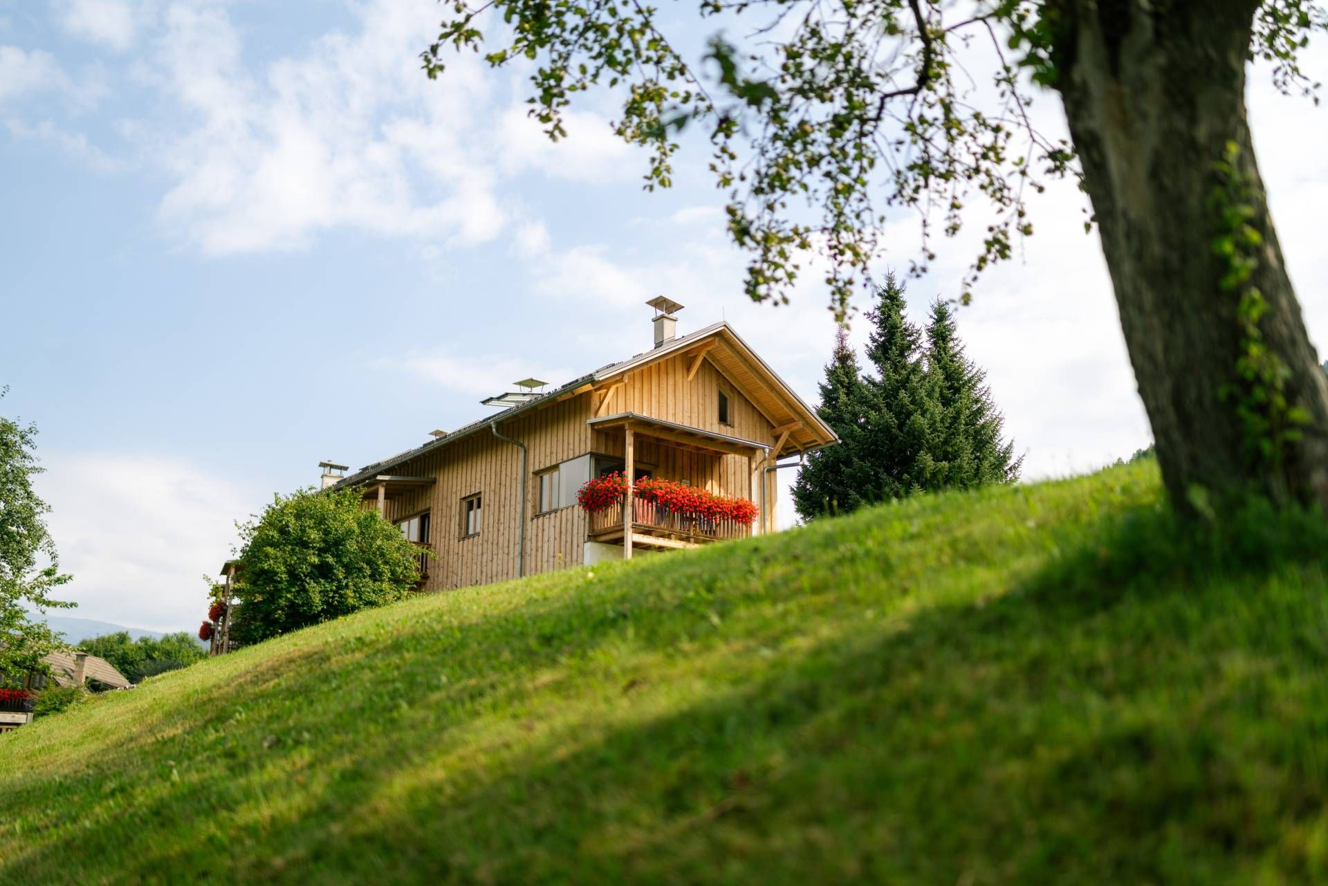 Blick von unten über eine Wiese zum Gebäude der Ferienwohnungen vom Mailädnerhof
